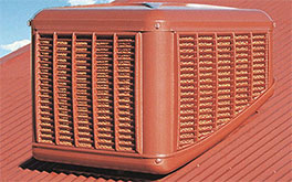 Coolbreeze red evaporative cooling system on a red metal roof against a blue sky with white clouds