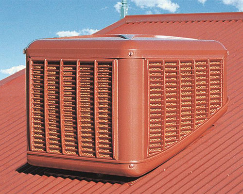 red coolbreeze cascade model evaporative cooler on red metal roof against a blue sky background with white clouds