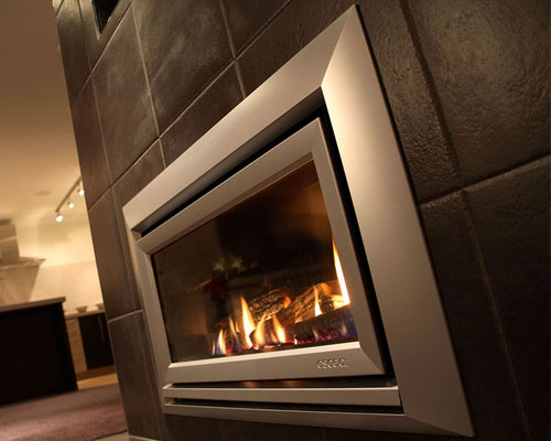 escea DL850 indoor gaslog fireplace on black tiled wall with silver frame and wooden fuel bed