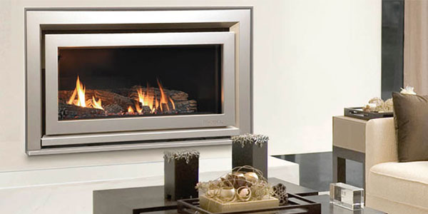ESCEA DL850 Indoor fireplace with silver border and wood aflame inside. built into a cream coloured wall with a coffee table in front of it