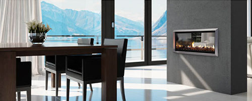 Escea DX1000 Indoor fireplace (gas) built into a coal coloured wall warming up a room with a scenic view of mountains outside